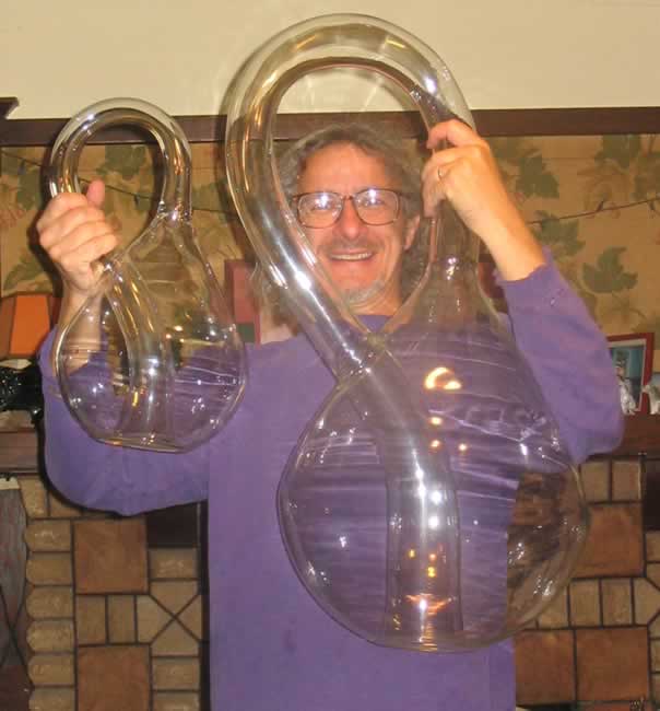 Cliff Stoll holding two oversized klein bottles and grinning enormously.